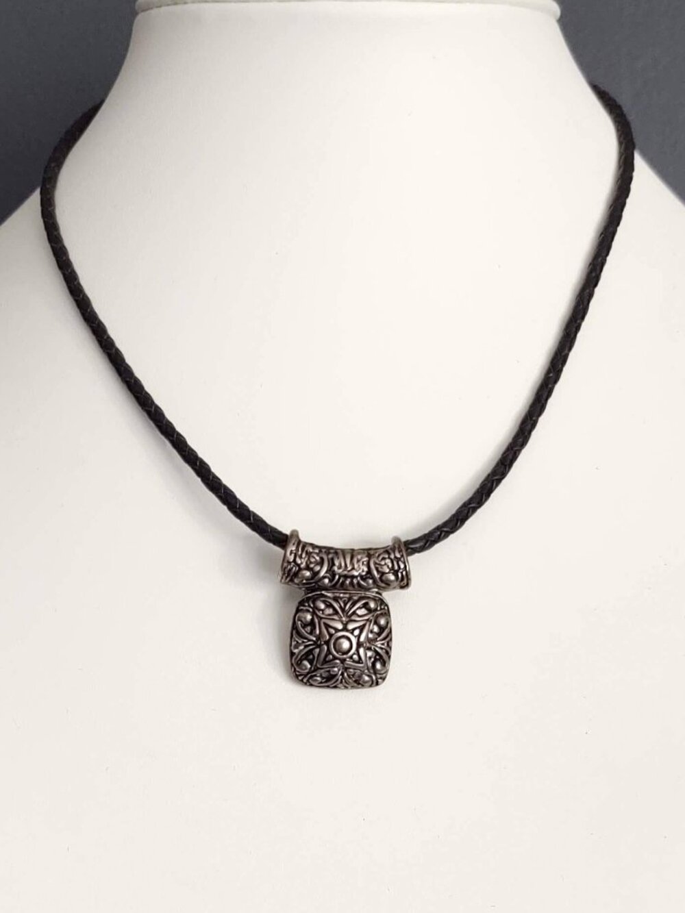 Silver pendant on black leather cording necklace